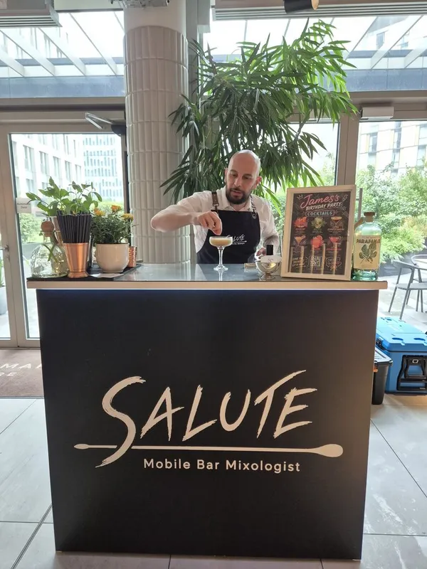 Two Salute bartenders serving a guest at the mobile bar
